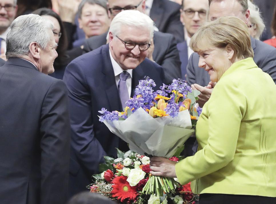 Blumen für den künftigen Herrn im Schloss Bellevue: Frank-Walter Steinmeier nimmt kurz nach Bekanntgabe seiner Wahl zum zwölften deutschen Bundespräsidenten am 12. Februar 2017 im Berliner Reichstag die Glückwünsche von Amtsvorgänger Joachim Gauck und Bundeskanzlerin Angela Merkel entgegen. PICTURE ALLIANCE/AP PHOTO/MARKUS SCHREIBER