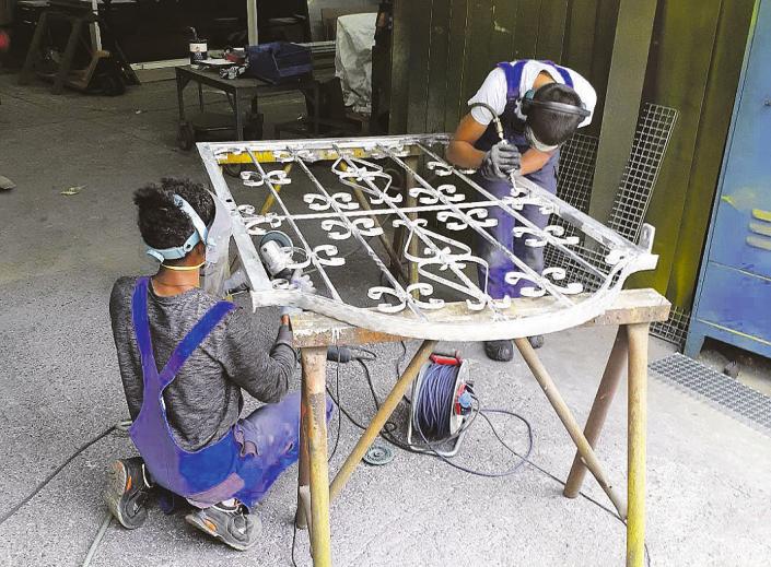 Auszubildende bei Arno Mistereck beputzen ein schmiedeeisernes Tor zur anschließenden Nachverzinkung Fotos: Tina Jordan Auszubildende bei Arno Mistereck beputzen ein schmiedeeisernes Tor zur anschließenden Nachverzinkung Fotos: Tina Jordan
